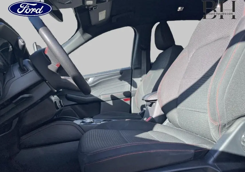 Vue intérieure côté gauche du Ford Kuga 2023, sièges sport noirs avec surpiqûres rouges et volant cuir multifonction.