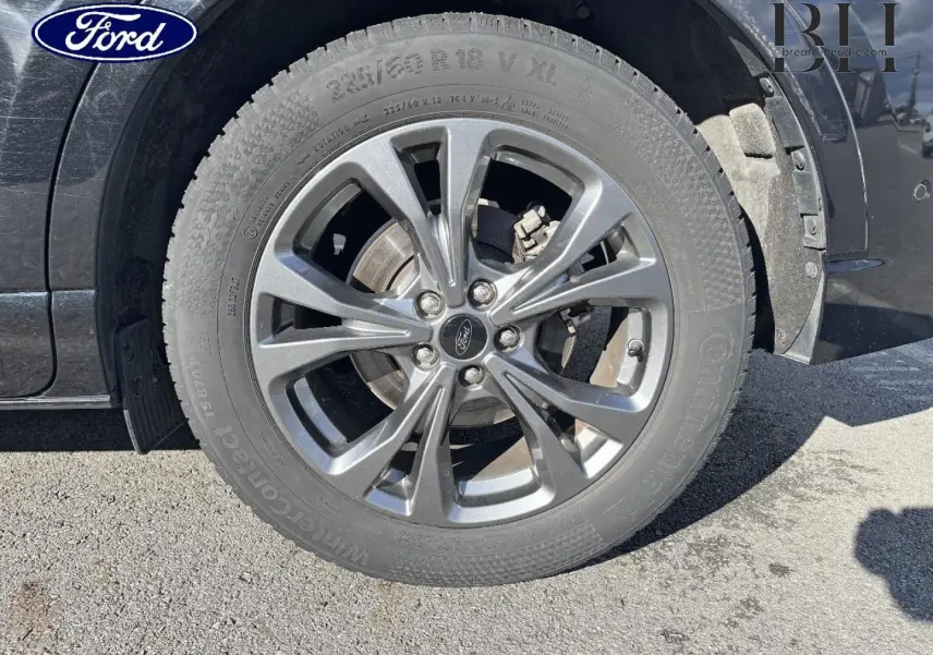 Gros plan sur la jante alu gris foncé et le pneu du côté avant droit d’un Ford Kuga noir Agate Métallisée.