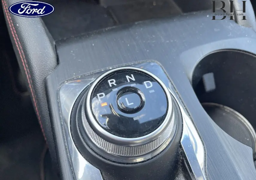 Gros plan sur la molette de boîte automatique du Ford Kuga noir Agate Métallisée, avec console centrale et porte-gobelets visibles.
