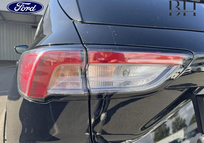 Gros plan sur le feu arrière droit d’un Ford Kuga noir Agate Métallisée 2023, avec reflet sur la carrosserie.