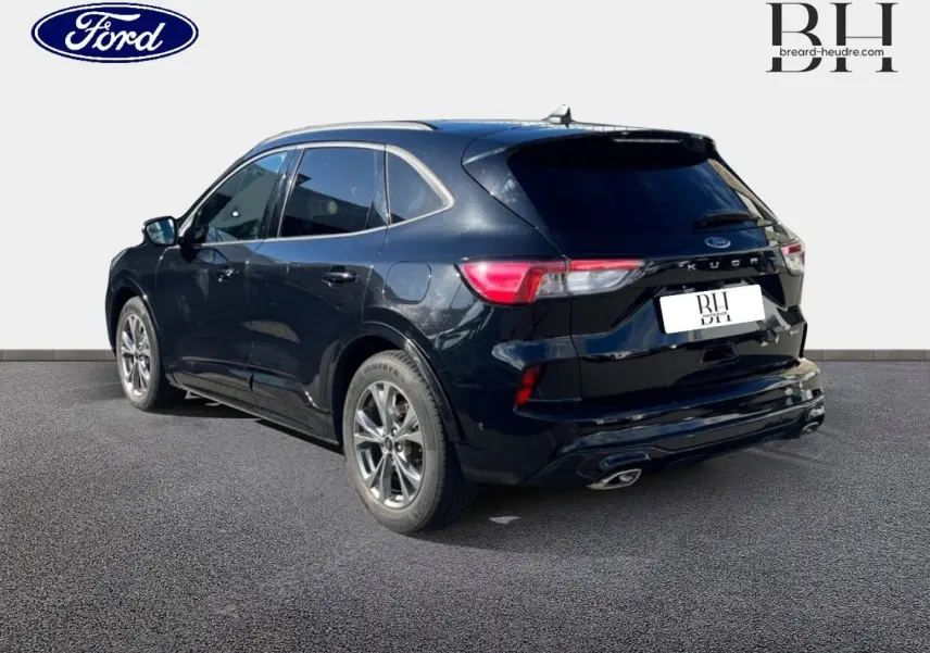 Ford Kuga noir Agate métallisé vu en 3/4 arrière droit, avec vitres arrière surteintées et double sortie d’échappement.