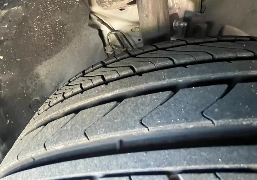 Gros plan sur le pneu arrière gauche du DS3 Crossback Performance Line gris, montrant la bande de roulement et l'intérieur de l'aile.