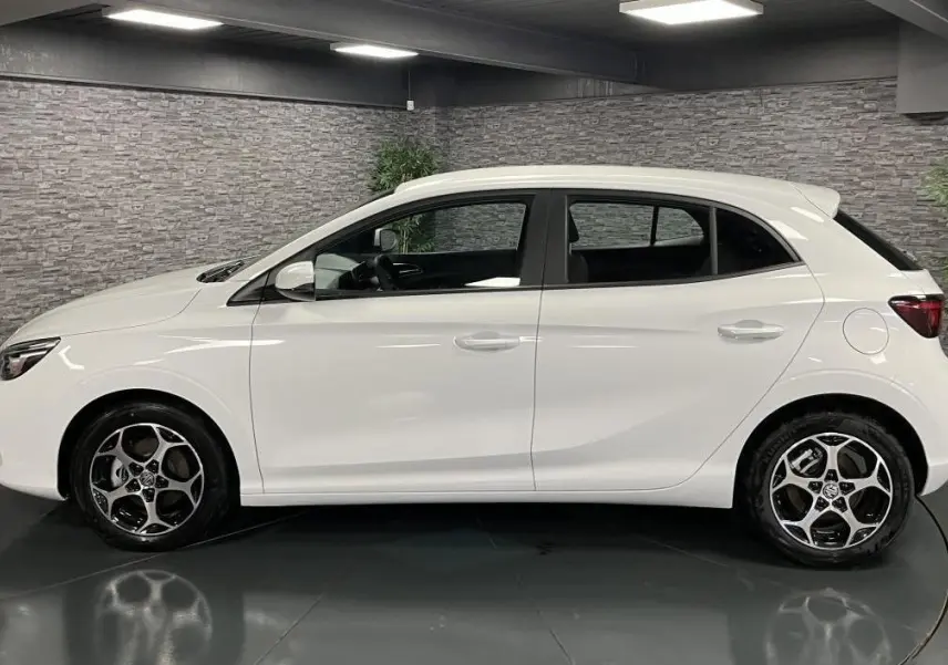 Vue latérale droite d'une MG3 1.5 Hybrid+ 195 Comfort blanche avec jantes alliage 16 pouces dans un showroom.