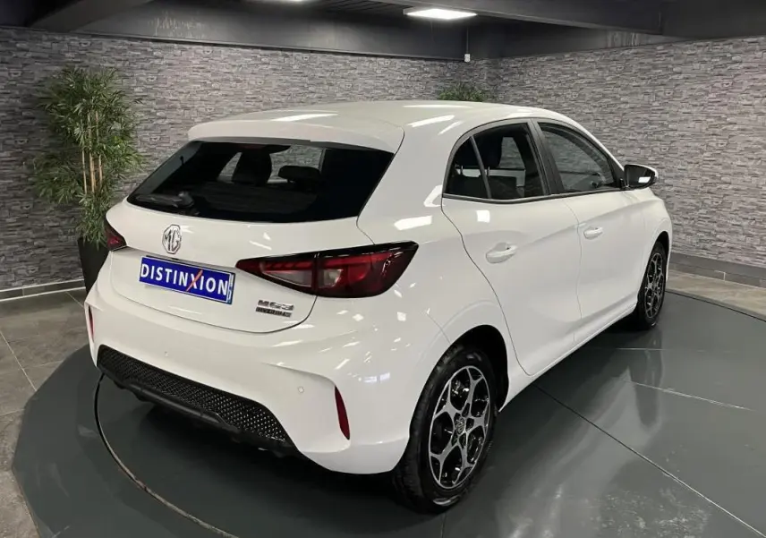Vue 3/4 arrière droite d'une MG3 blanche 2024 avec jantes alliage et feux arrière LED dans un showroom.