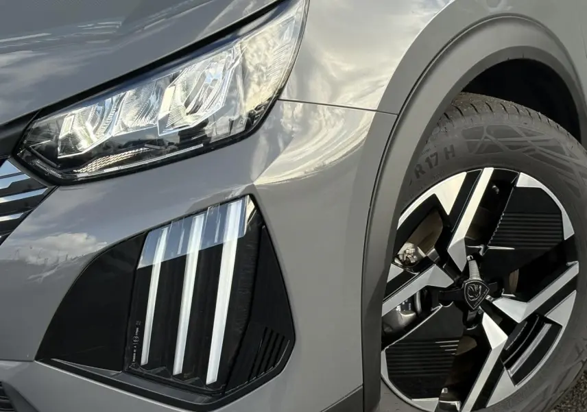 Gros plan sur l'avant droit gris Selenium du Peugeot 2008 Hybrid 145 avec feux LED 3 griffes et jante alliage 17 pouces.