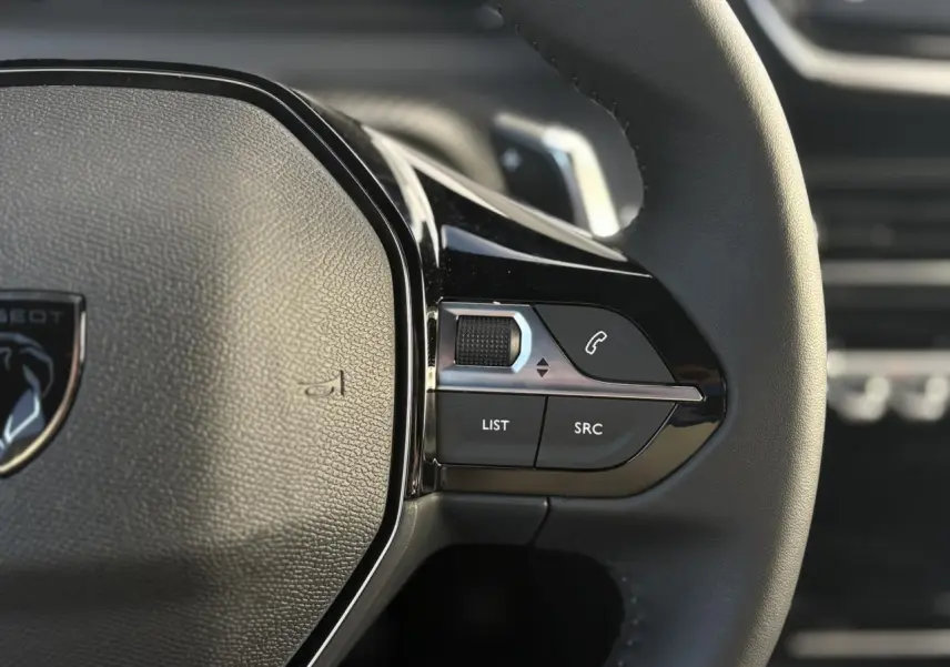 Gros plan sur les commandes multimédia à droite du volant cuir noir du Peugeot 2008 Hybrid 145 e-DSC6 Allure.