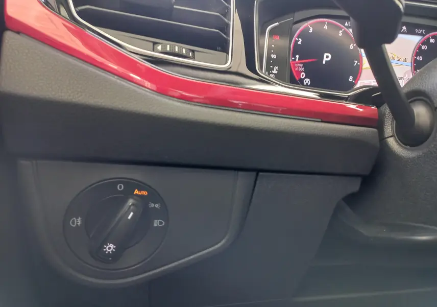 Gros plan sur le tableau de bord de la Volkswagen Polo 2024, avec bandeau rouge brillant et commandes d'éclairage.