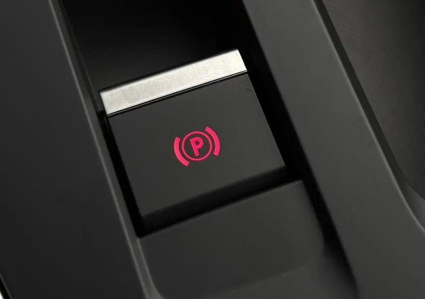 Gros plan sur le bouton de frein de stationnement électrique illuminé en rouge dans le console centrale du Citroën C5 Aircross.