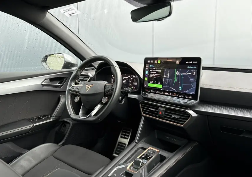 Vue intérieure côté conducteur du CUPRA LEON ST 2025, avec volant cuir, écran tactile HD et finition noire élégante.