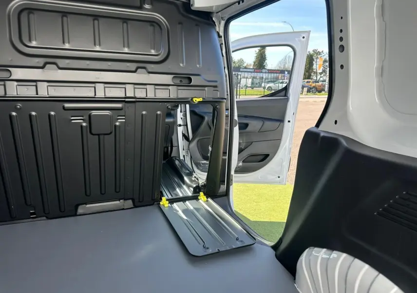 Vue rapprochée de l'espace entre les sièges arrière noirs du Citroën Berlingo III blanc, avec console centrale basse.