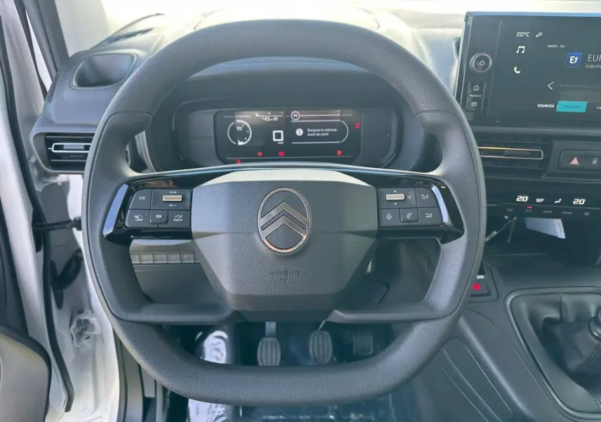 Vue rapprochée du volant multifonctions noir du Citroën Berlingo blanc Icy avec tableau de bord numérique et écran tactile.