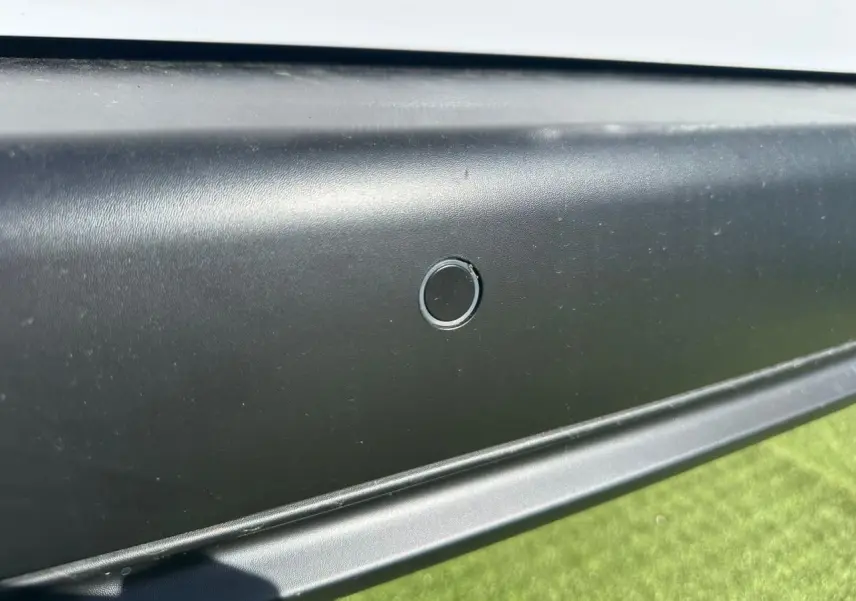 Gros plan sur le capteur de stationnement arrière noir du Citroën Berlingo blanc Icy, vue latérale basse.