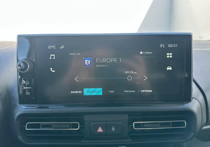 Écran tactile 10 pouces affichant la radio Europe 1, tableau de bord noir du Citroën Berlingo blanc, vue intérieure frontale.
