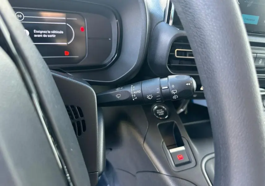 Vue intérieure rapprochée du tableau de bord et du volant du Citroën Berlingo blanc, avec commandes et affichage digital.