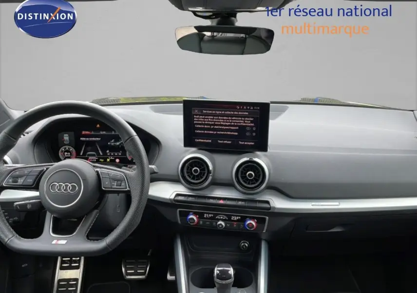 Vue intérieure avant de l'Audi Q2 35 2.0 TDI S-Line 2025 avec tableau de bord noir et écran central tactile.
