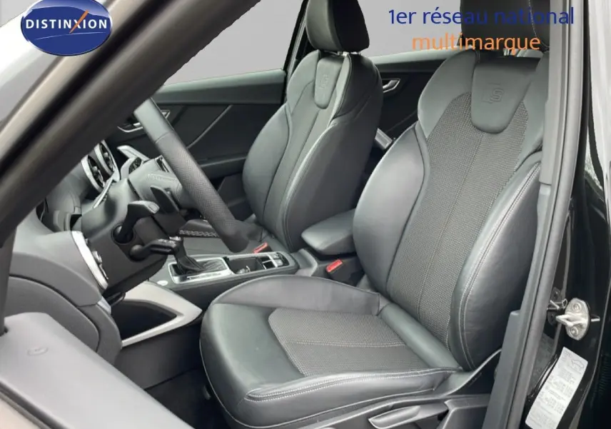 Vue intérieure côté conducteur de l'Audi Q2 S-Line 2025 avec sièges en cuir noir et volant multifonction.