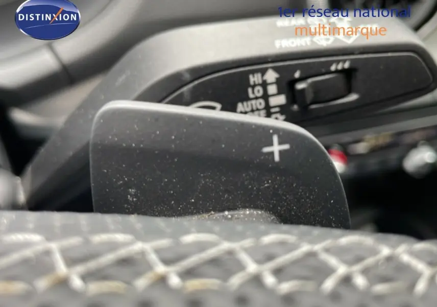 Gros plan sur la palette de changement de vitesse "+" du volant cuir noir de l'Audi Q2 2025 finition S-Line.