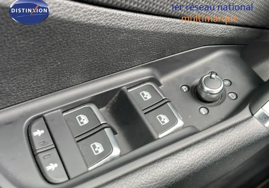 Gros plan sur les commandes de lève-vitres et rétroviseurs côté conducteur de l'Audi Q2 noir mito metal 2025.