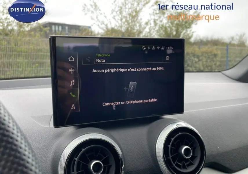 Écran tactile central et aérateurs ronds du tableau de bord d’un Audi Q2 noir mito metal, vue intérieure avant.