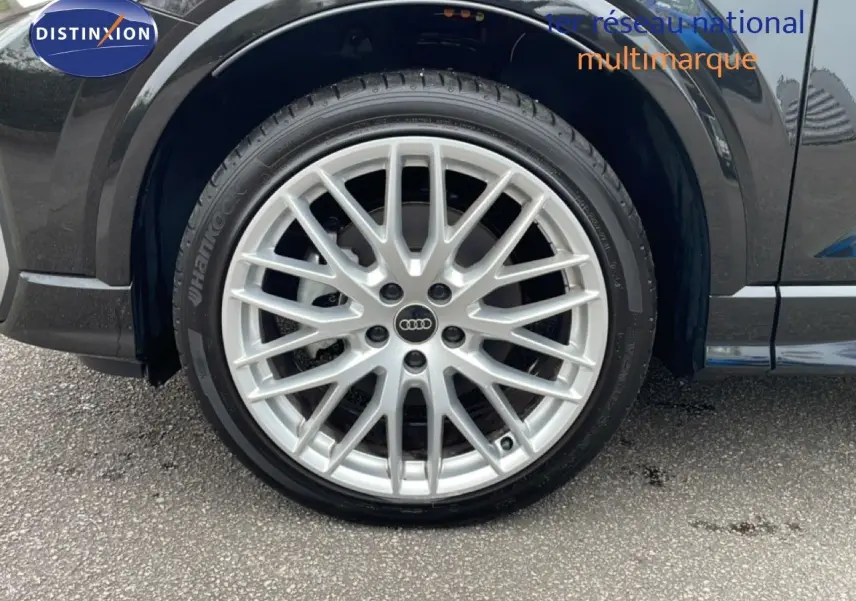 Gros plan sur la roue avant gauche d’un Audi Q2 noir mito metal avec jante alliage multi-branches argentée.
