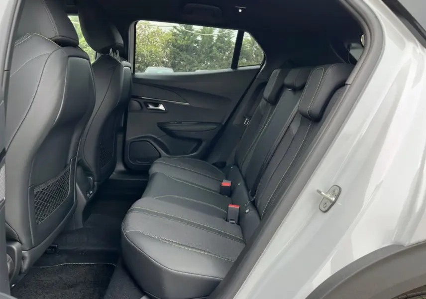 Vue latérale droite de l’habitacle arrière du Peugeot 2008 blanc, avec sièges en cuir noir et surpiqûres vertes.