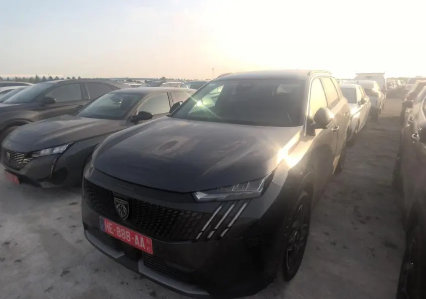 PEUGEOT 5008 gris foncé vue 3/4 avant droit, avec calandre noire et phares LED distinctifs au soleil couchant.
