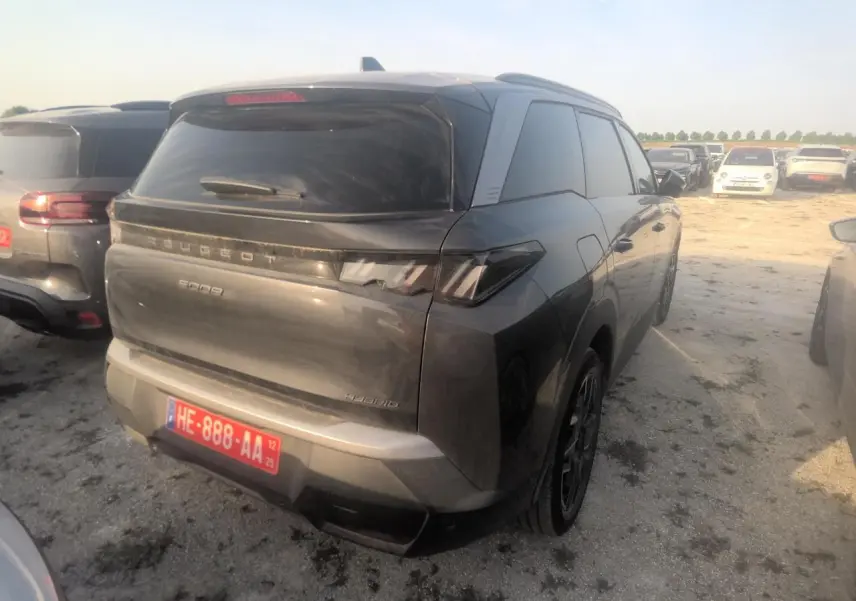 Vue 3/4 arrière droite d’un Peugeot 5008 gris foncé avec vitres teintées et feux arrière LED distinctifs.