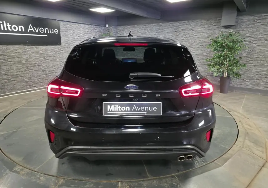 Vue arrière d'une Ford Focus noire 2024 avec feux LED allumés et double sortie d'échappement côté droit.