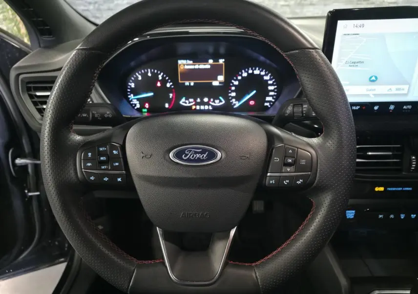 Vue intérieure centrée sur le volant ST Line en cuir noir avec surpiqûres rouges et tableau de bord numérique Ford Focus 2024.