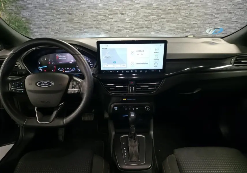 Vue intérieure avant de la Ford Focus 2024 noire, tableau de bord avec écran tactile central et volant multifonction.