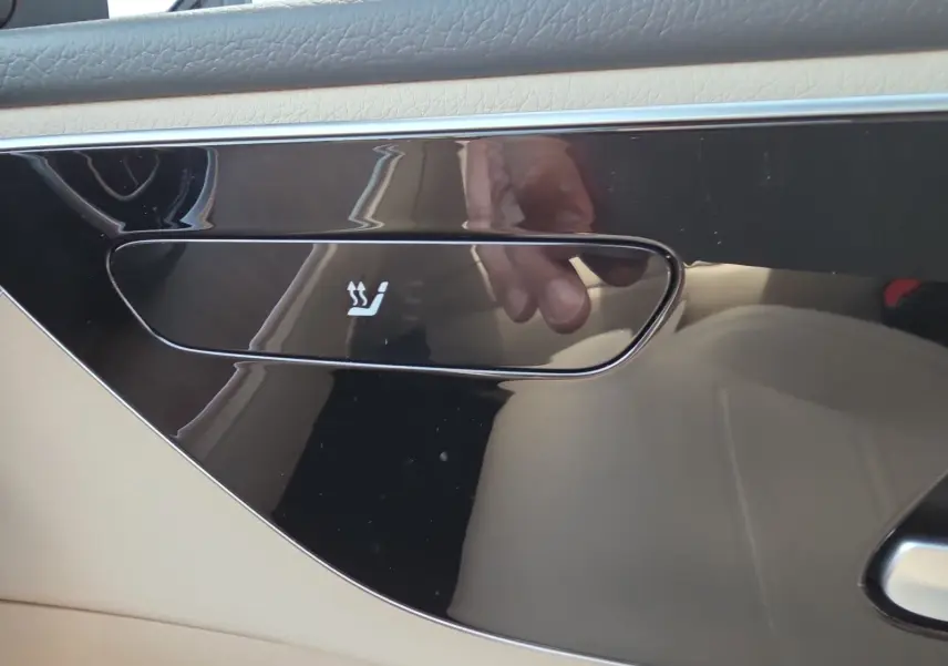 Bouton de siège chauffant sur panneau de porte intérieur beige et noir d'une Mercedes Classe C Break 220 D 4MATIC.