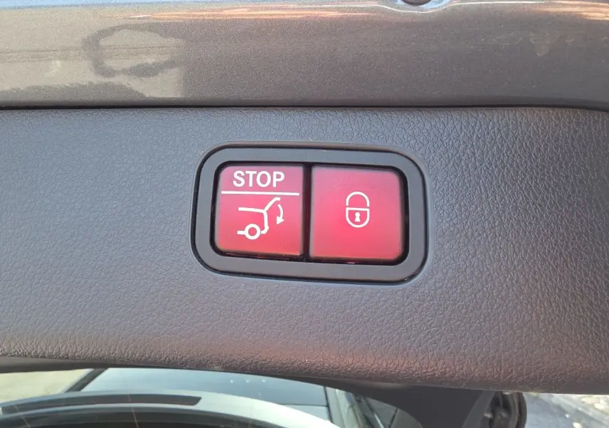 Gros plan sur les boutons rouges d'ouverture et verrouillage du hayon électrique d'un Mercedes Classe C Break gris foncé.