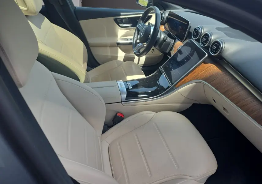 Vue intérieure côté conducteur de la Mercedes Classe C Break 220 D 4MATIC avec sellerie cuir beige et tableau de bord bois.