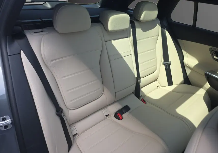 Vue intérieure des sièges arrière en cuir beige clair d’un Mercedes Classe C Break gris foncé, avec ceinture de sécurité noire.