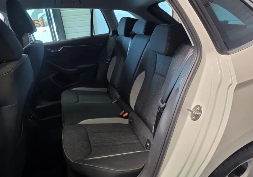Vue intérieure côté arrière droit de la Skoda Scala blanche 2020, montrant la banquette arrière en tissu bicolore gris et noir.