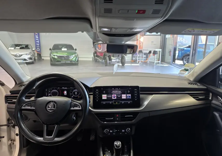 Vue intérieure avant du tableau de bord noir et écran tactile central d'une Skoda Scala blanche de 2020 avec boîte manuelle.