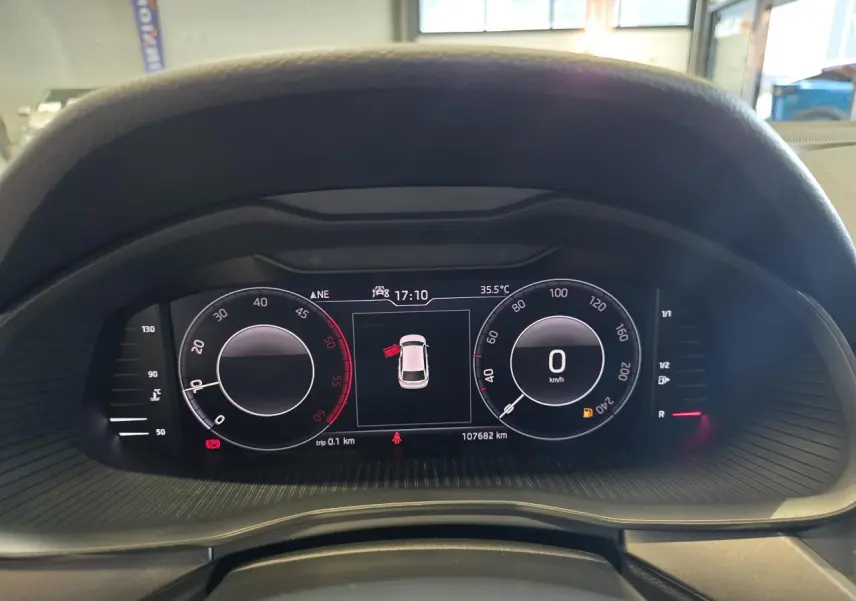 Tableau de bord numérique du Skoda Scala blanc, affichant vitesse à 0 km/h et porte ouverte, vue de face rapprochée.