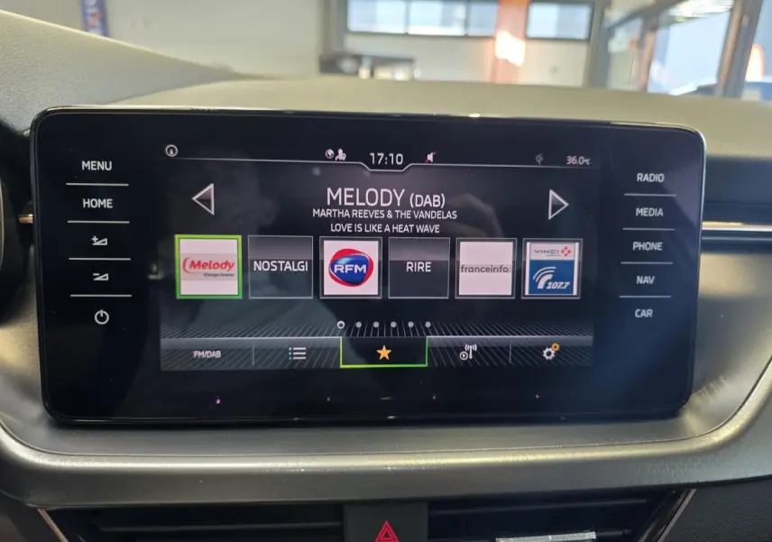 Écran tactile central du tableau de bord d'une Skoda Scala blanche, affichant les stations radio numériques.