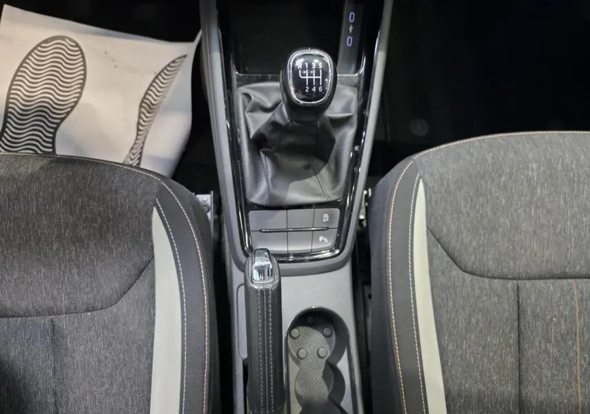 Vue plongeante sur la console centrale d’une Skoda Scala blanche, avec levier de vitesses manuel et frein à main en cuir.