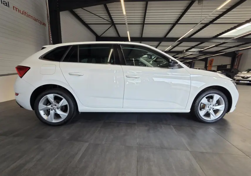 Vue latérale droite d'une Skoda Scala blanche 2020 en showroom, avec jantes alliage argent et vitres teintées.