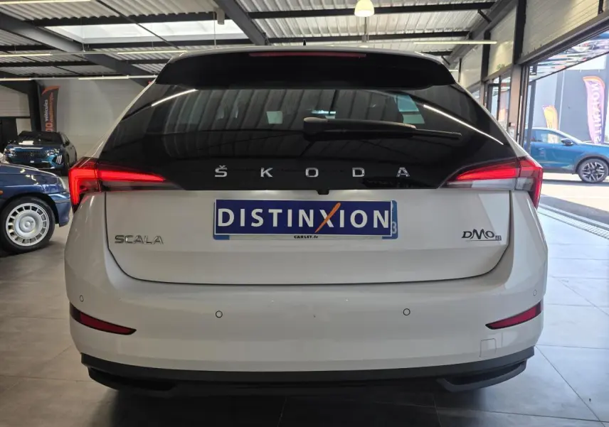 Vue arrière d'une Skoda Scala blanche avec feux LED et hayon noir dans un showroom.