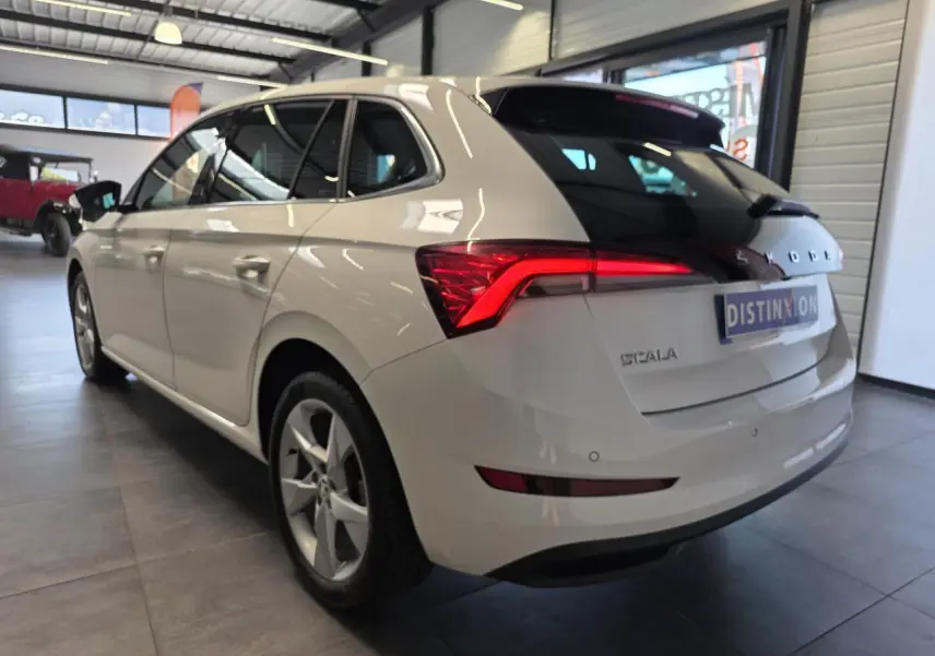 Vue 3/4 arrière droite d'une Skoda Scala blanche avec feux arrière LED et jantes alliage en showroom.
