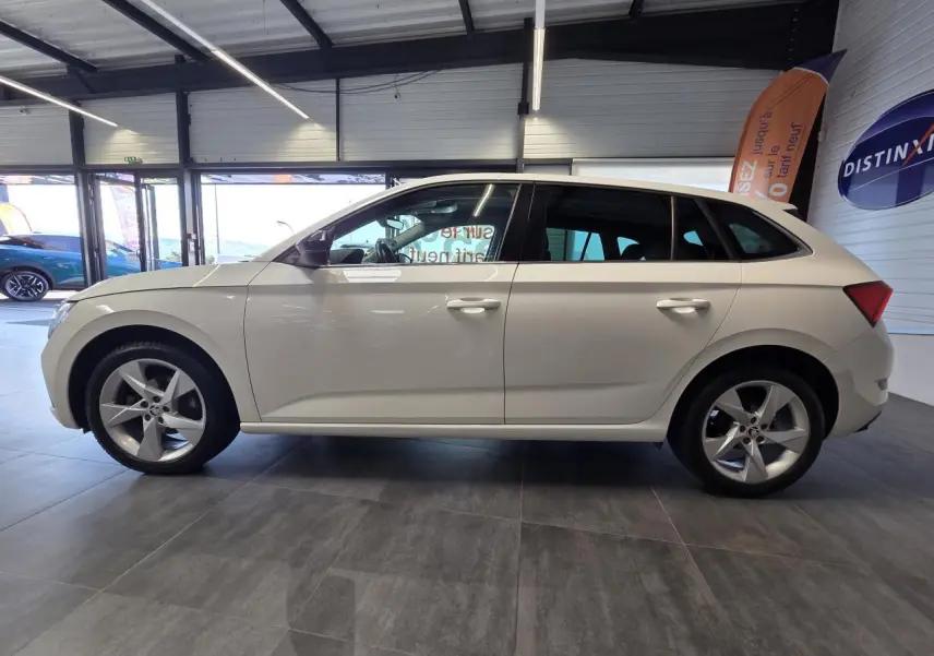 Vue de profil côté gauche d'une Skoda Scala blanche 2020 avec jantes alliage 17 pouces dans un showroom.