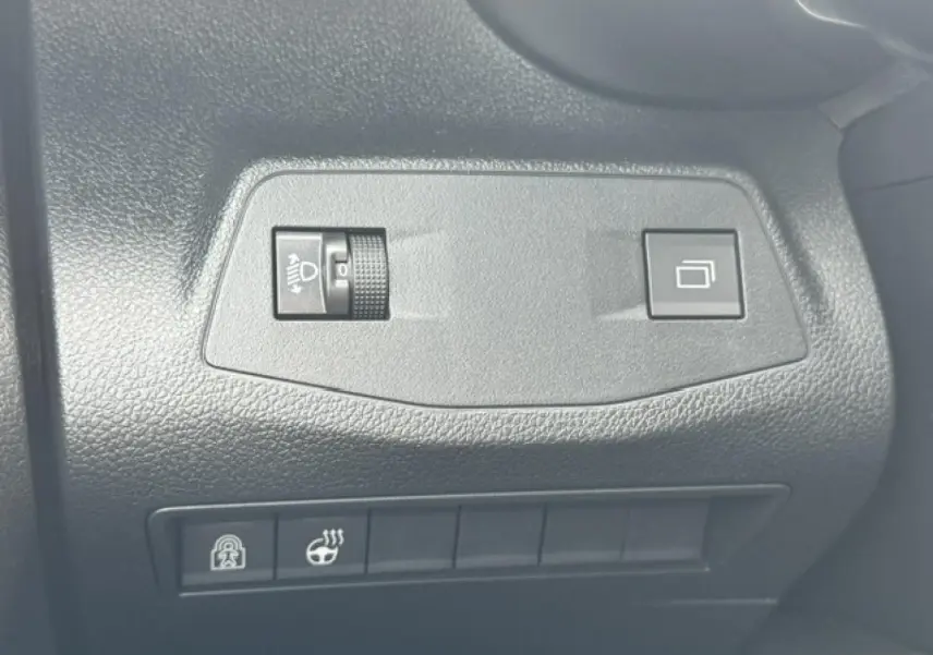 Détail des commandes de réglage des phares et verrouillage dans l'habitacle d'un Citroën Berlingo gris acier.