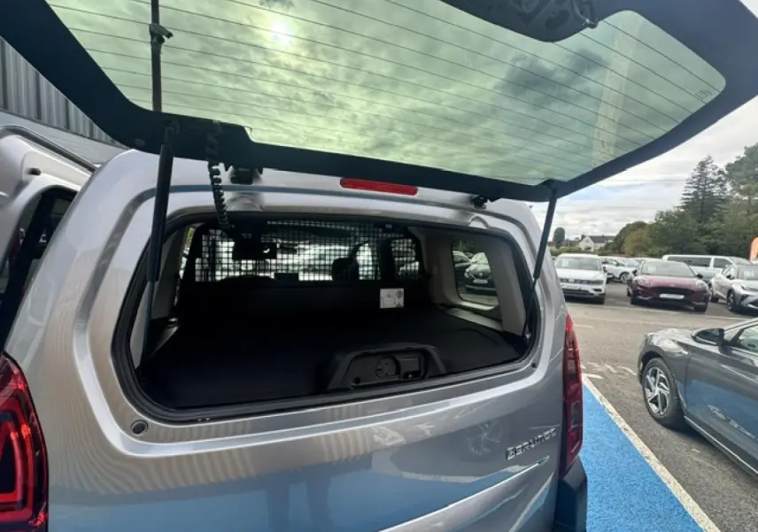 Vue arrière ouverte du Citroën Berlingo gris acier, montrant l'espace de chargement avec séparation intérieure.