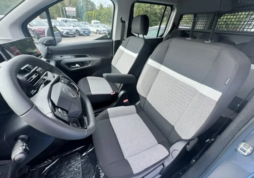 Intérieur avant du Citroën Berlingo gris acier, vue côté conducteur montrant les sièges tissu bicolore et le volant multifonction.