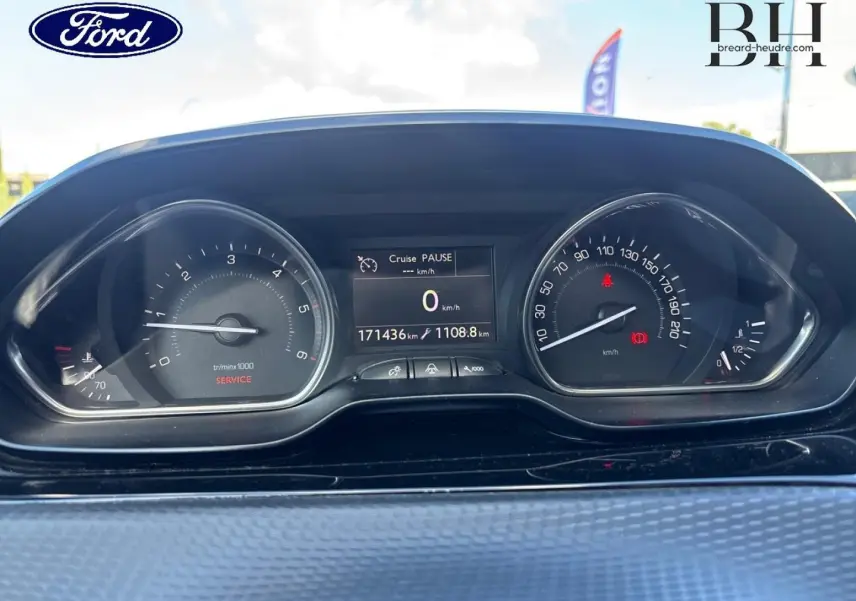 Vue rapprochée du tableau de bord d'un Peugeot 2008 gris, affichant le compteur et l'ordinateur de bord.