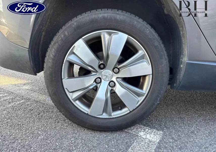 Gros plan sur la roue avant droite d’un Peugeot 2008 gris Spirit avec jante alliage à 5 branches doubles.