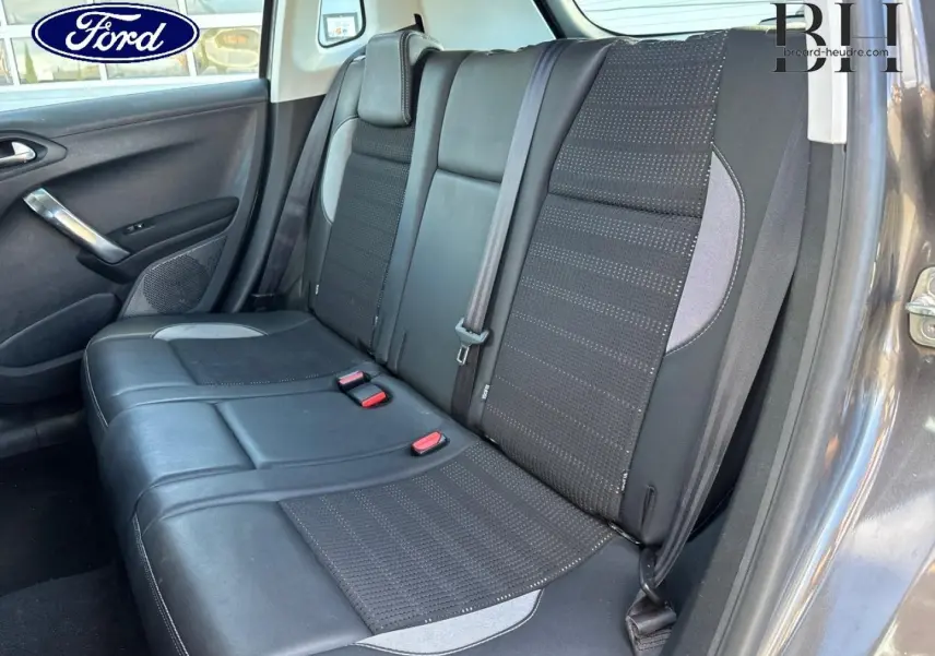 Vue intérieure montrant la banquette arrière en cuir et tissu noir du Peugeot 2008 Spirit Grey, côté droit ouvert.