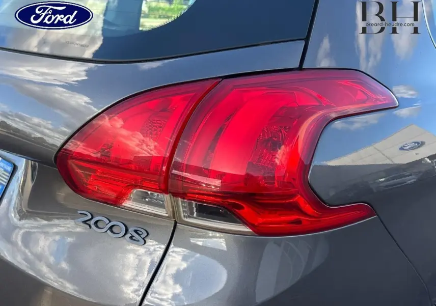 Gros plan sur le feu arrière droit d’un Peugeot 2008 gris Spirit avec logo et badge visibles.